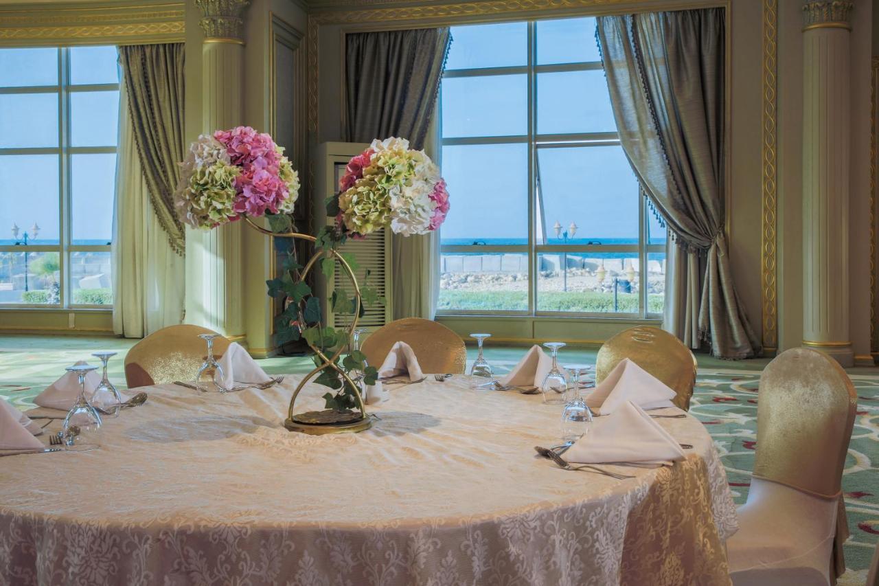 โรงแรมซันไรส์ อเล็กซ์ อเวนิว อเล็กซานเดรีย ภายนอก รูปภาพ The photo depicts a beautifully arranged round dining table set in an elegant room. The table is covered with a light-colored lace tablecloth and features an artistic floral centerpiece with pink and white flowers. The place settings include folded n