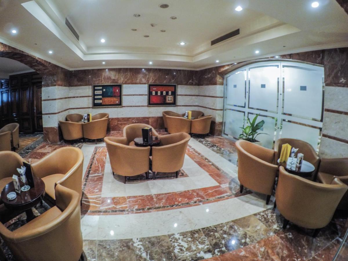 โรงแรมซันไรส์ อเล็กซ์ อเวนิว อเล็กซานเดรีย ภายนอก รูปภาพ The photo depicts a stylish lounge area with several comfortable seating arrangements. There are plush, curved chairs arranged around small tables, likely intended for coffee or casual gatherings. The floor features a polished marble design, and the 